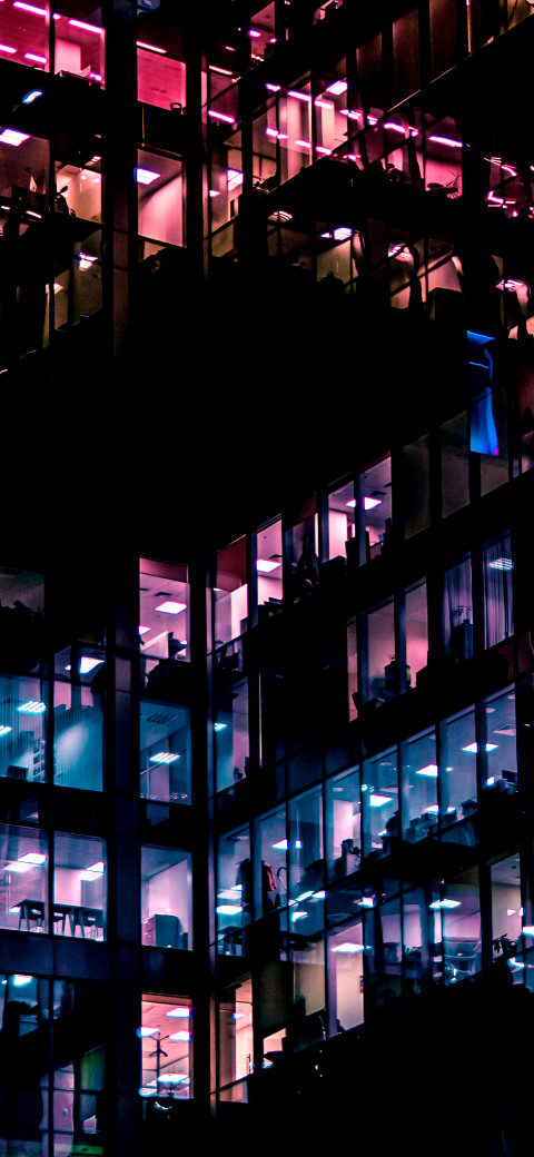 nighttime view of a building with people in the windows