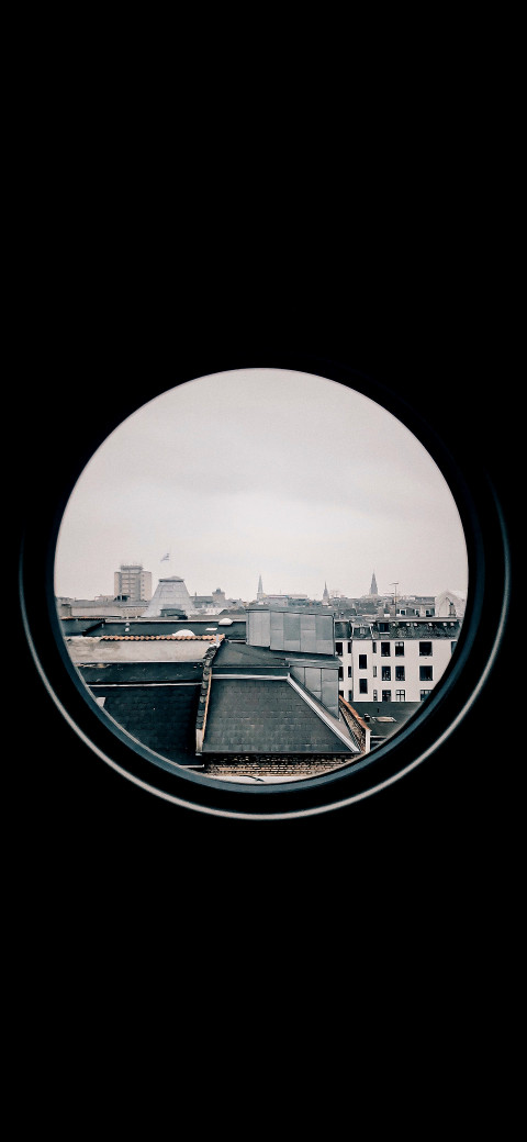 A view of a round window with a city in the background