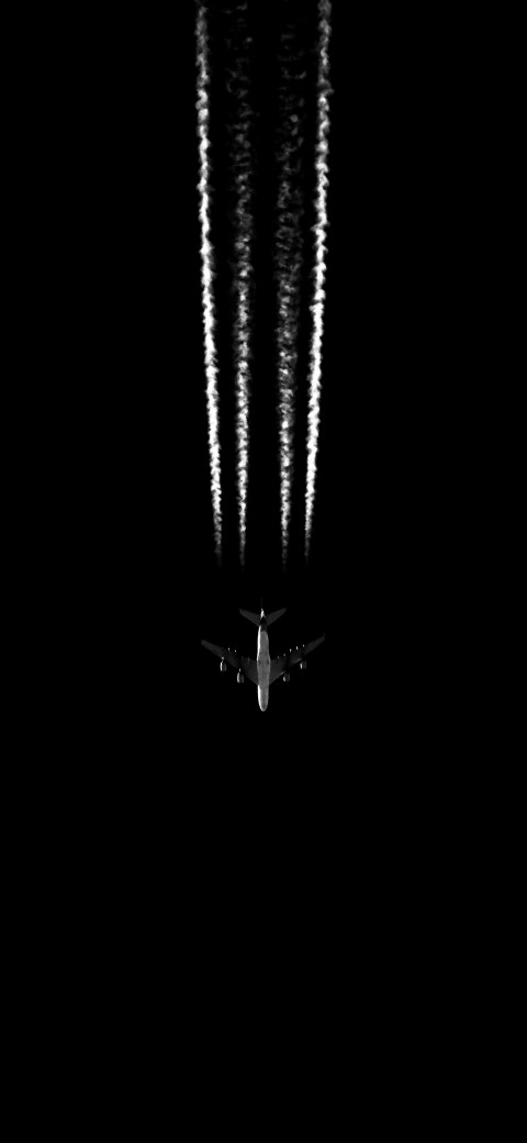 aeroplane flying in the dark with smoke trails behind it