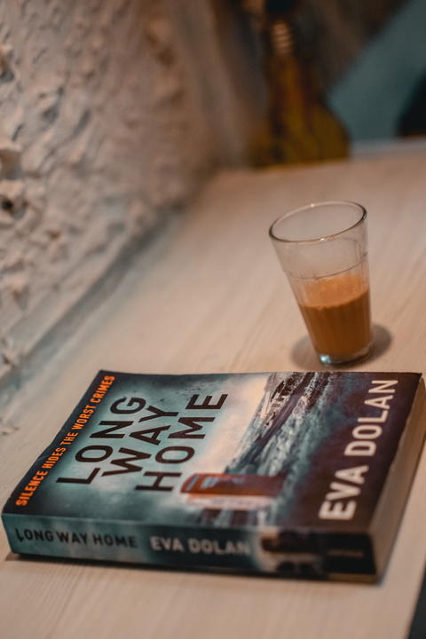 Free photo of Book 'Long Way Home' and Tea in glass tumbler on table