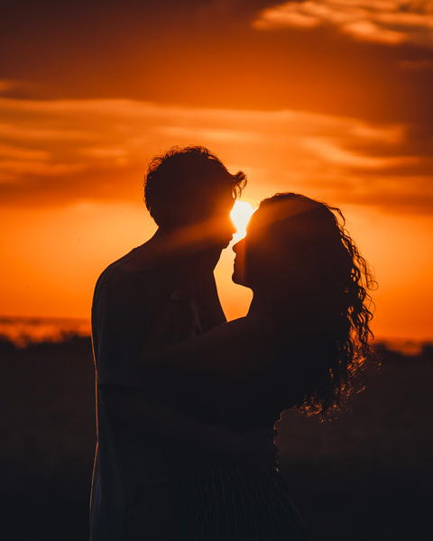 Free photo of couple in silhouette with sun setting behind them