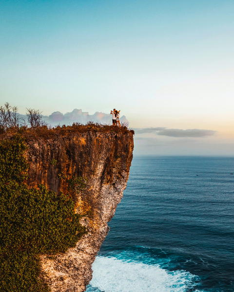 Free photo of couple standing on a cliff overlooking the ocean