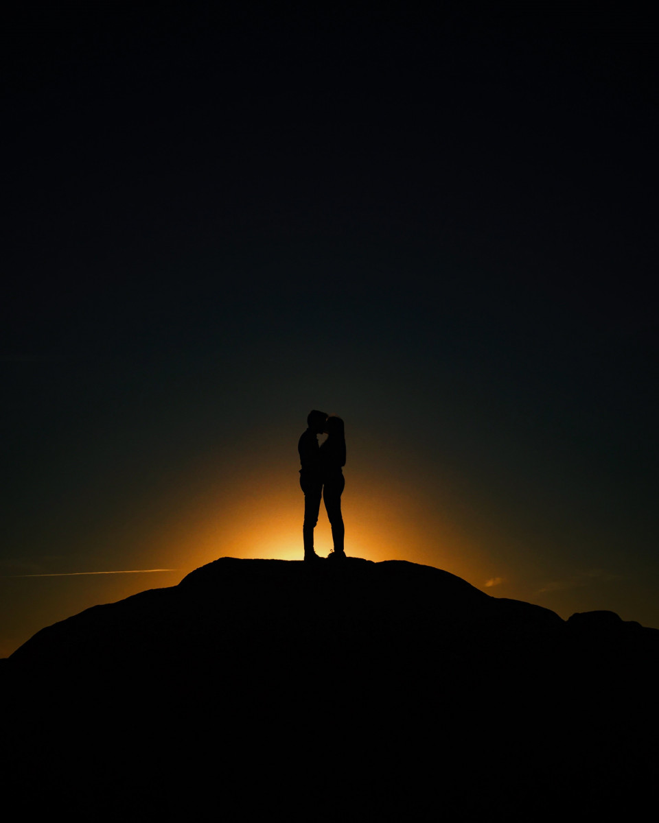 Free photo of couple standing on a hill at sunset