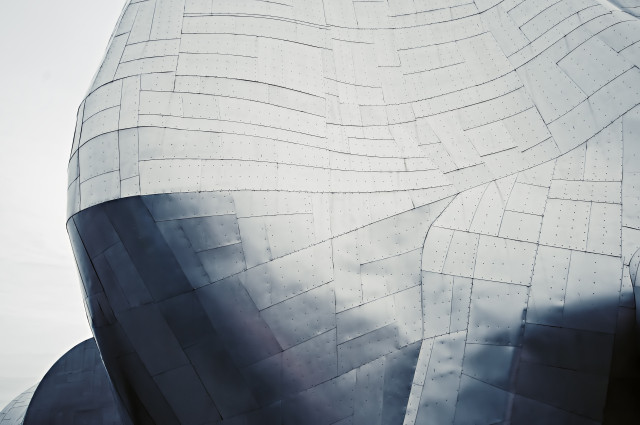 A close-up of the iconic metallic facade of the Museum of Pop Culture in Seattle, Washington, featuring intricate geometric patterns and a reflective surface