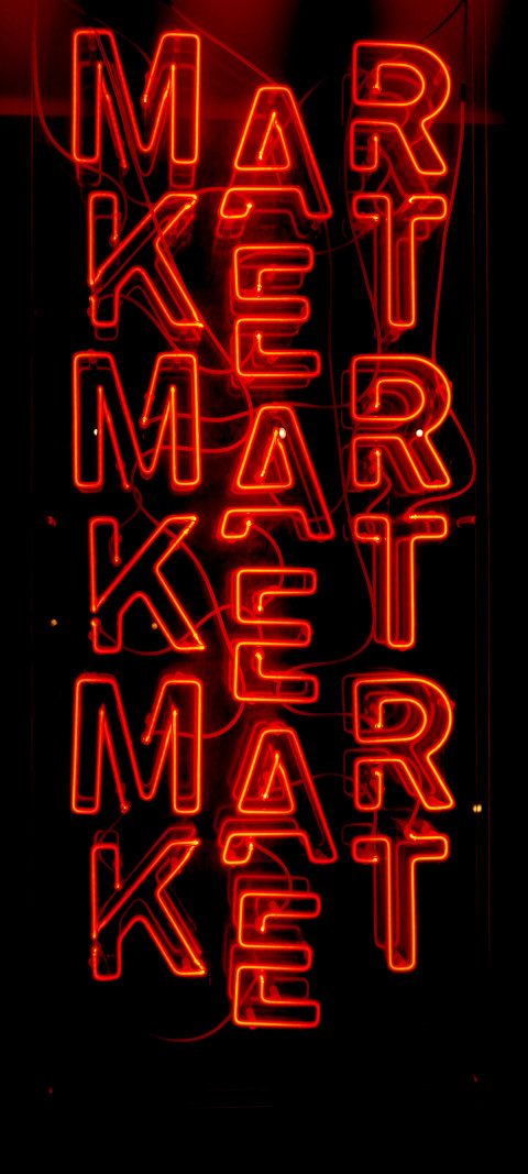 neon sign of a market with a red light in the background