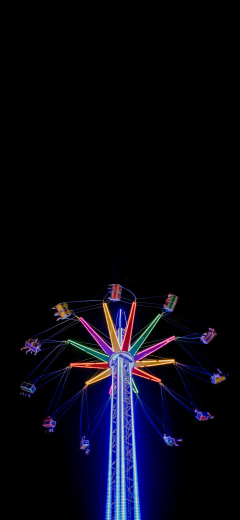 rides at night with colorful lights and a black background