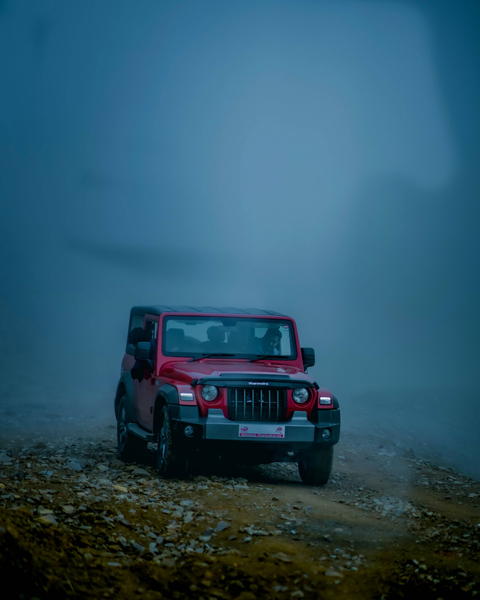 Free photo of mahindra thar jeep driving on a foggy road in the middle of the day