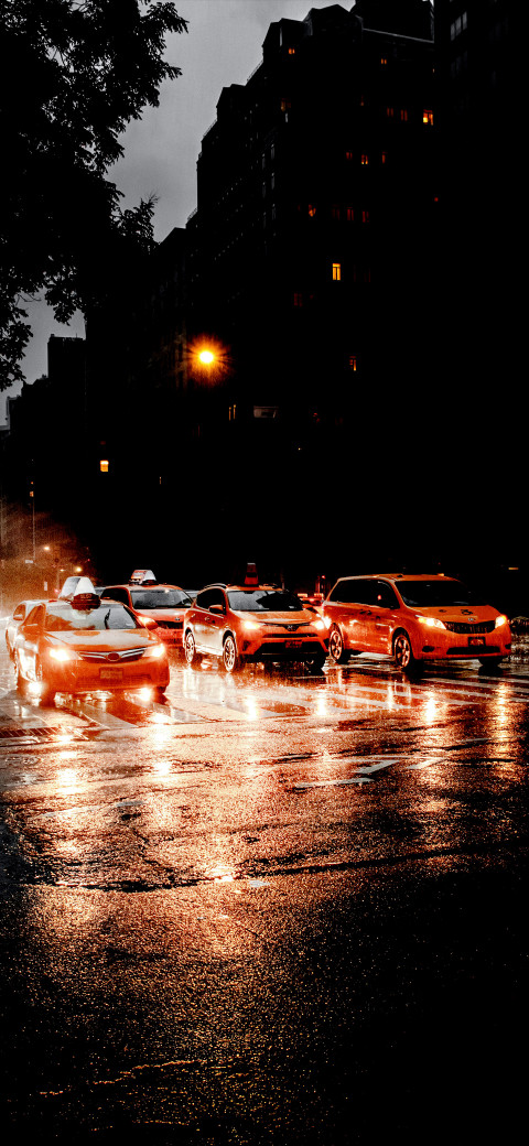 Cars are driving down a wet street at night in the rain
