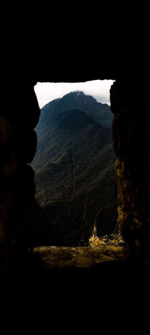 view of a mountain through a window in stone wall