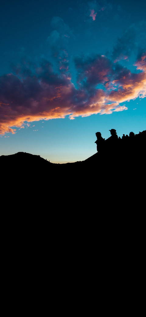 silhouette of a person standing on a hill at sunset