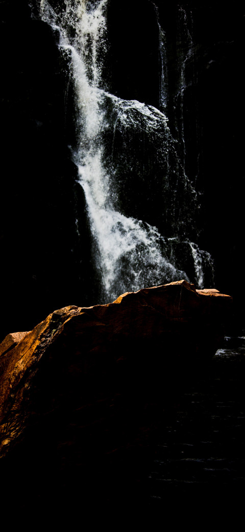 waterfall in the dark with a rock in the foreground
