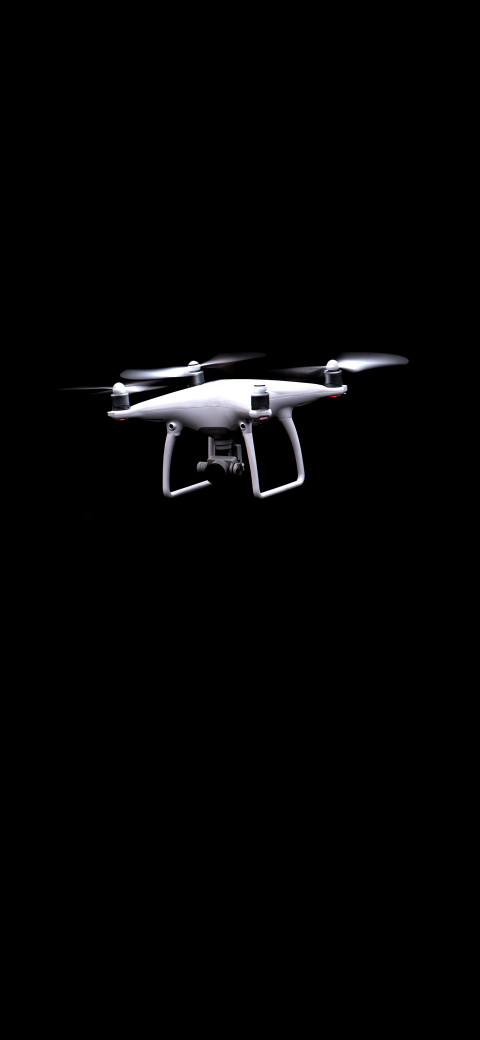 a close up of a white drone flying in the dark