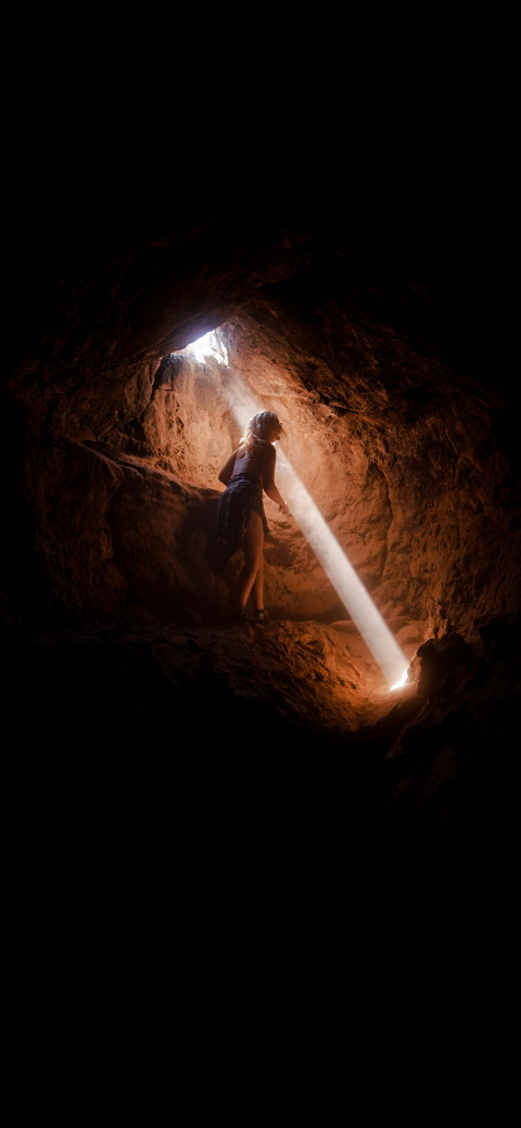 woman walking through a cave with a light beam coming out of it