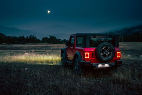 Free photo of red mahindra thar parked in a field at night