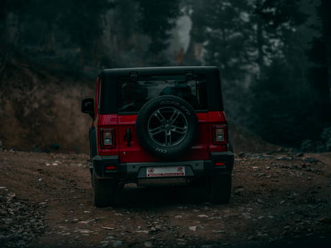 Free photo of red mahindra thar parked on a dirt road in the woods