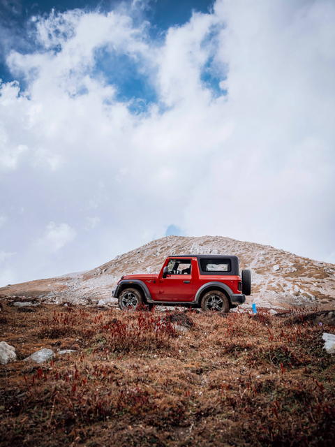 Free photo of red Mahindra Thar parked on a hill with a blue bottle