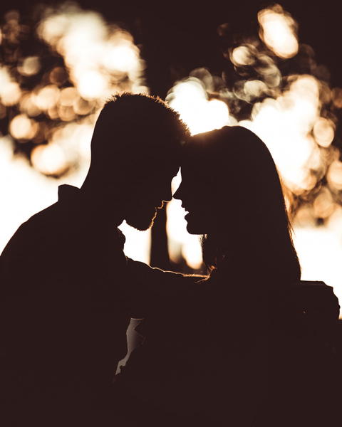 Free photo of silhouette of a couple in the dark with a tree in the background