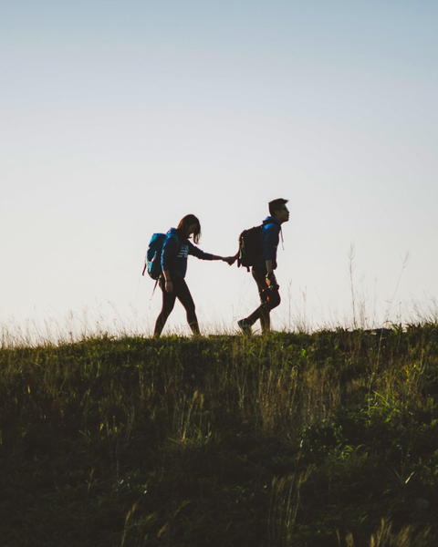 Free photo of there are two people walking on a hill holding hands