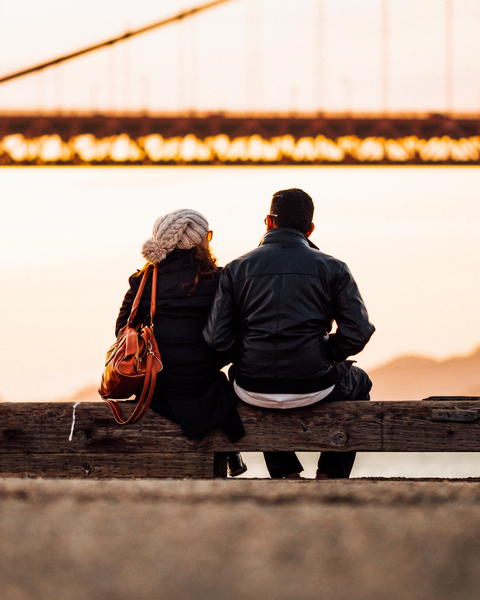 Free photo of two people sitting on a bench looking at the bridge