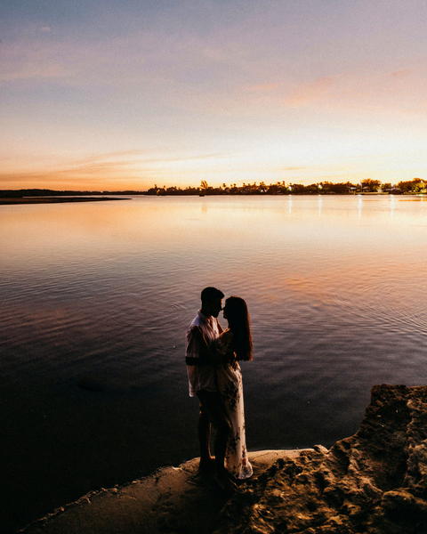 Free photo of two people standing on a rock by the water