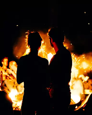 a man and woman standing in front of a fire