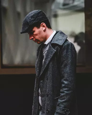 a man in a coat and hat looking down