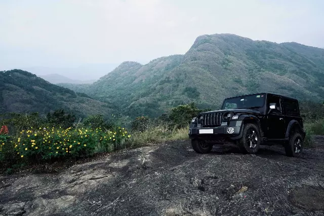 black Mahindra Thar parked on a rocky road near a mountain