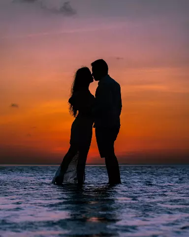 couple kissing in the water at sunset on the beach