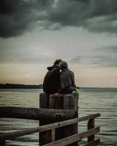 couple sitting on a wooden pier looking out at the water