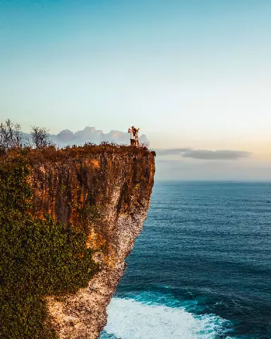 couple standing on a cliff overlooking the ocean