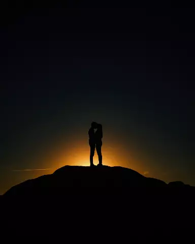 couple standing on a hill at sunset