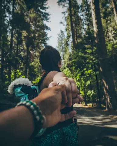 holding a woman's hand in the middle of a forest