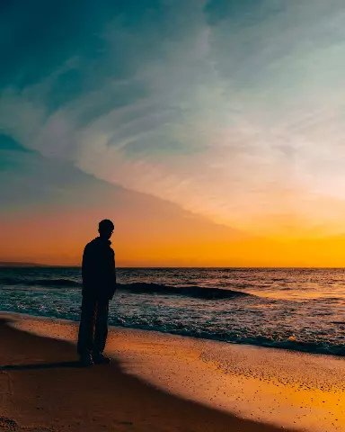 man standing on the beach watching the sunset