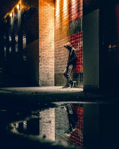 Man walking down a street at night with a hoodie on