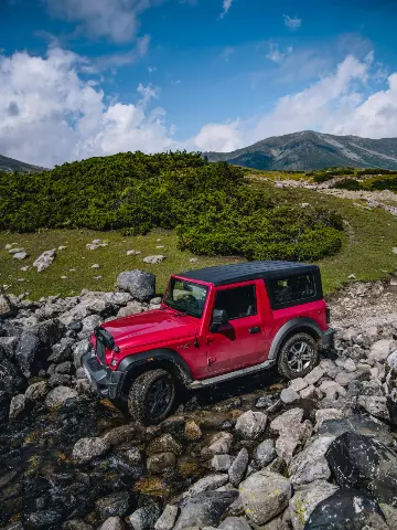 red Mahindra Thar driving on a rocky trail