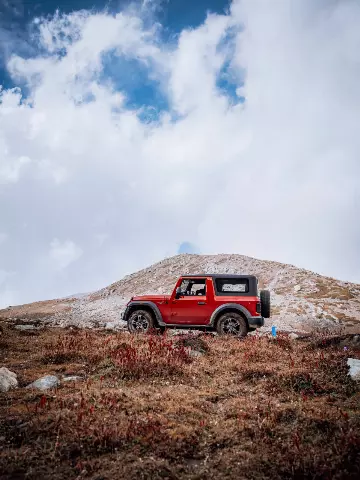 red Mahindra Thar parked on a hill with a blue bottle