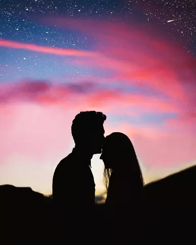 silhouette of a couple kissing in front of a colorful sky