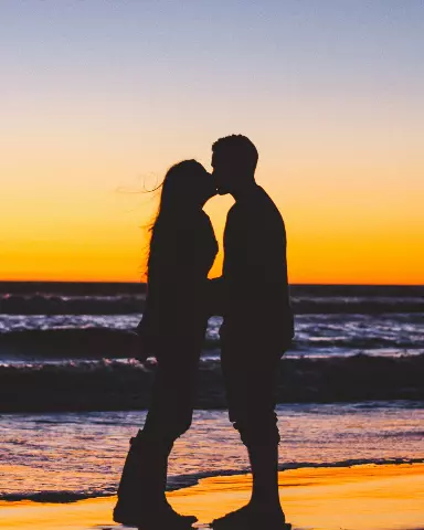 silhouette of a couple kissing on the beach at sunset
