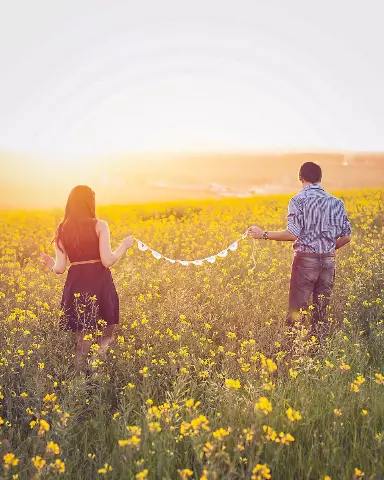 two people standing in a field holding a string